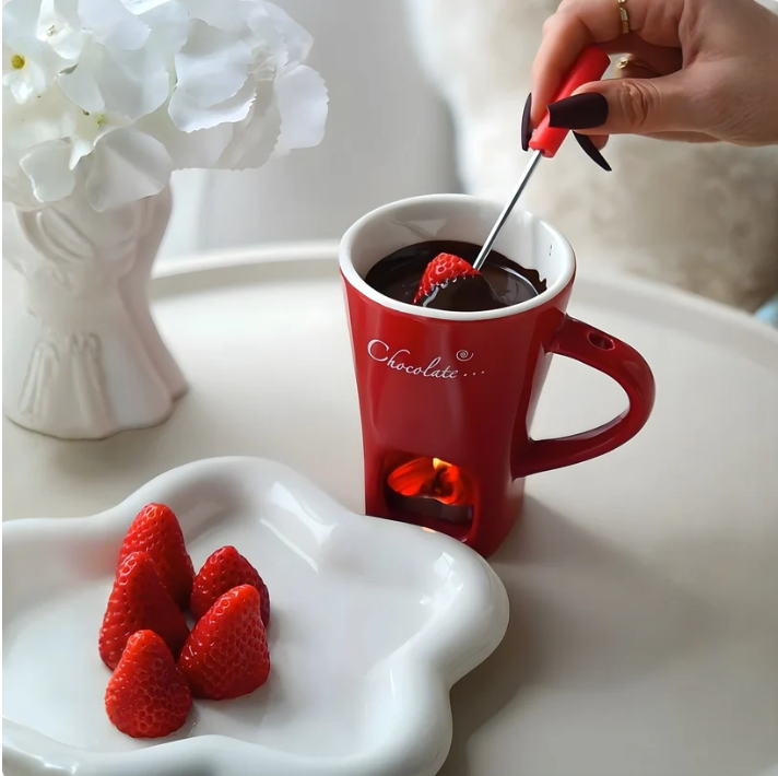 Rode chocoladefondue mok met een aardbei aan het vorkje